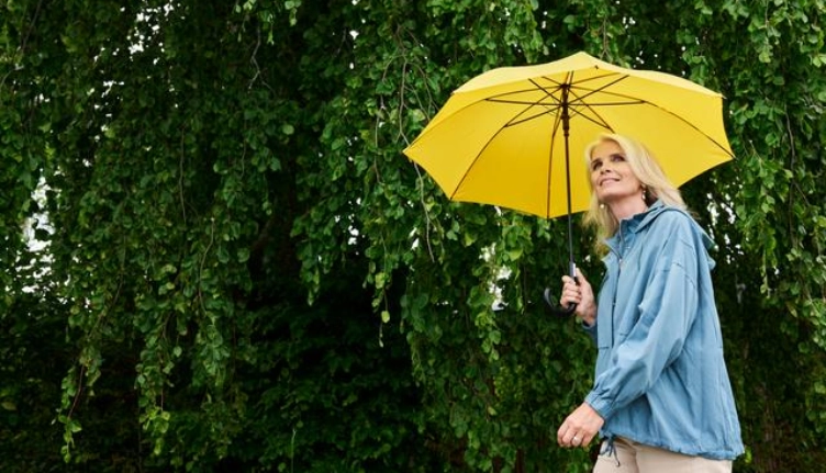 Frau mit gelbem Regenschirm - vermittelt den Eindruck von Sicherheit durch eine Kreditversicherung