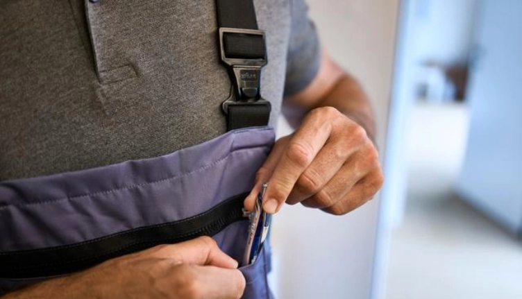 Person in einem Arbeitsanzug versorgt seinen Stift nach Abschluss einer Leasingversicherung