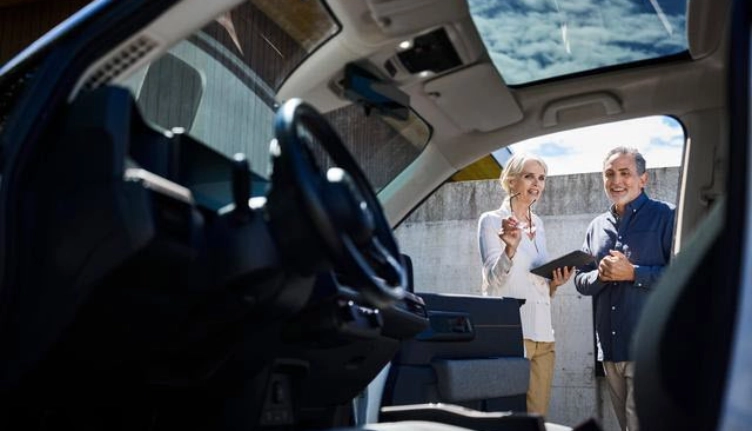Übergabesituation beim Leasing - Blick vom Fahrersitz nach draussen zu den zwei Personen