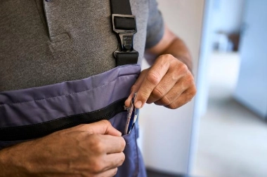 Person in einem Arbeitsanzug versorgt seinen Stift nach Abschluss einer Leasingversicherung