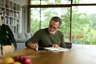 Mann bei der Durchsicht von Unterlagen am Tablet - steht für bewusste Absicherung durch eine Kreditversicherung