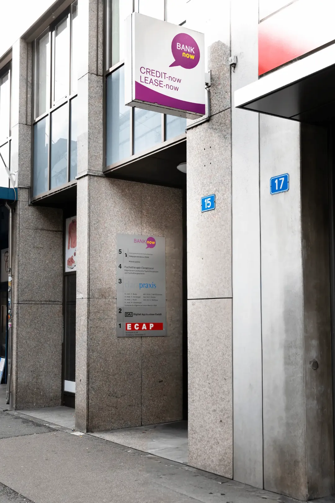 Zweiter Blick auf den Eingang der BANK-now Filiale Basel mit Schildern und Hausnummern.