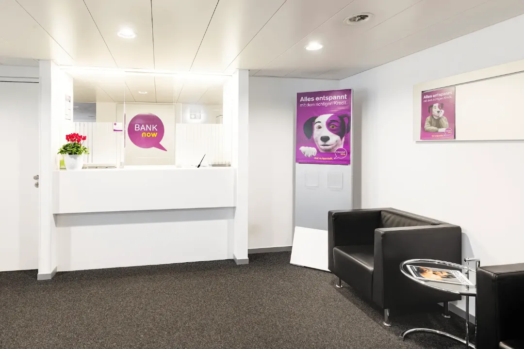 Wartebereich der BANK-now Filiale Basel mit Sitzgelegenheiten und Postern.