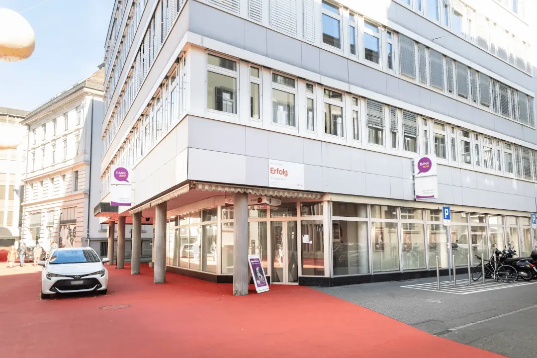 Zweite Aussenansicht der BANK-now Filiale St. Gallen mit Gebäudeecke, Eingang und sichtbarer Signaletik.