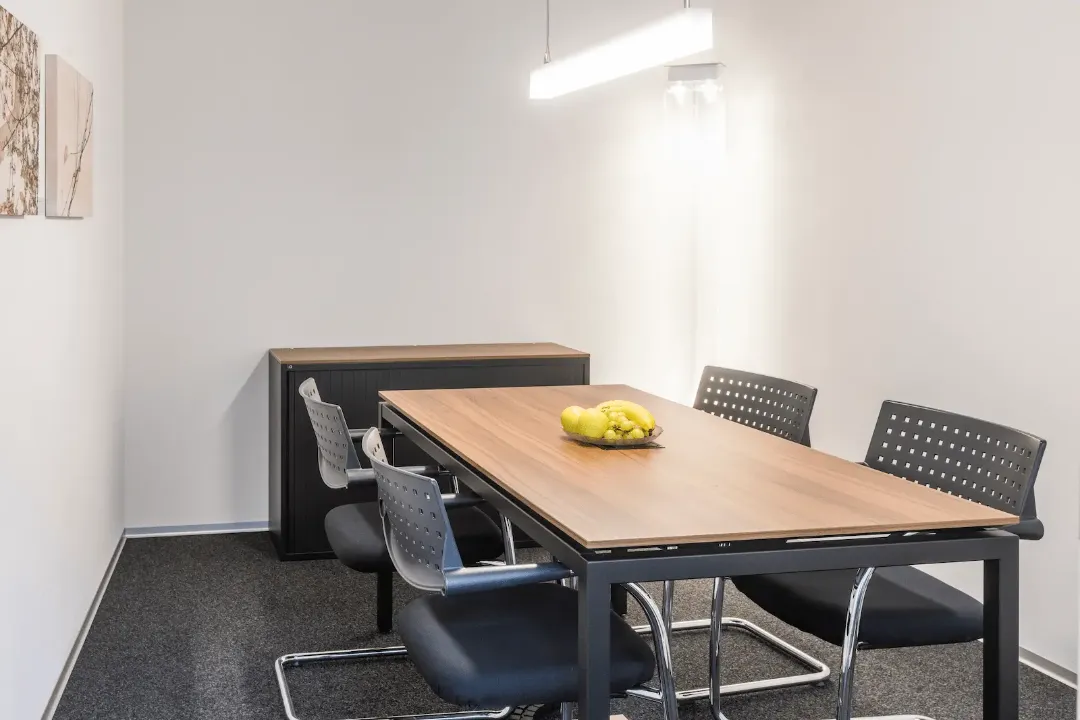 Besprechungsraum der BANK-now Filiale Uster mit Tisch, vier Stühlen und Sideboard im Hintergrund.