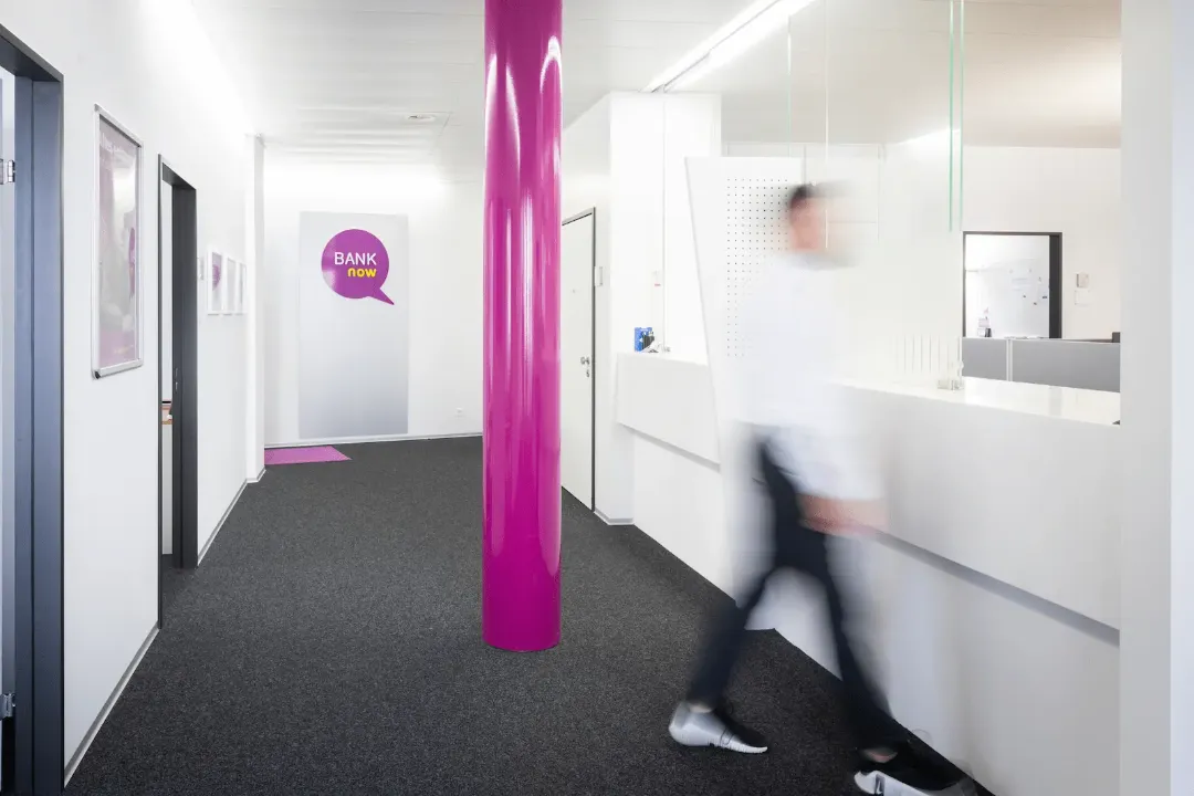 Eingangsbereich der BANK-now Filiale Zürich mit pinker Säule und Blick zum Empfang.