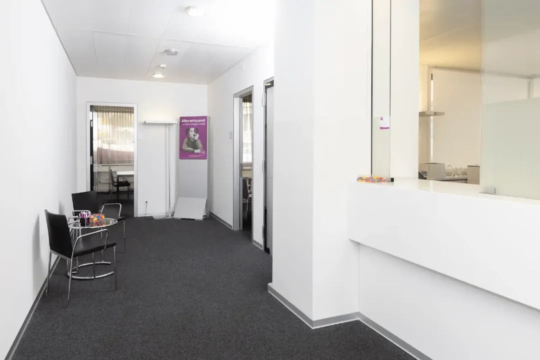 Schalterbereich der BANK-now Filiale Zürich-Oerlikon mit hellem Innenraum und Plakat im Hintergrund.