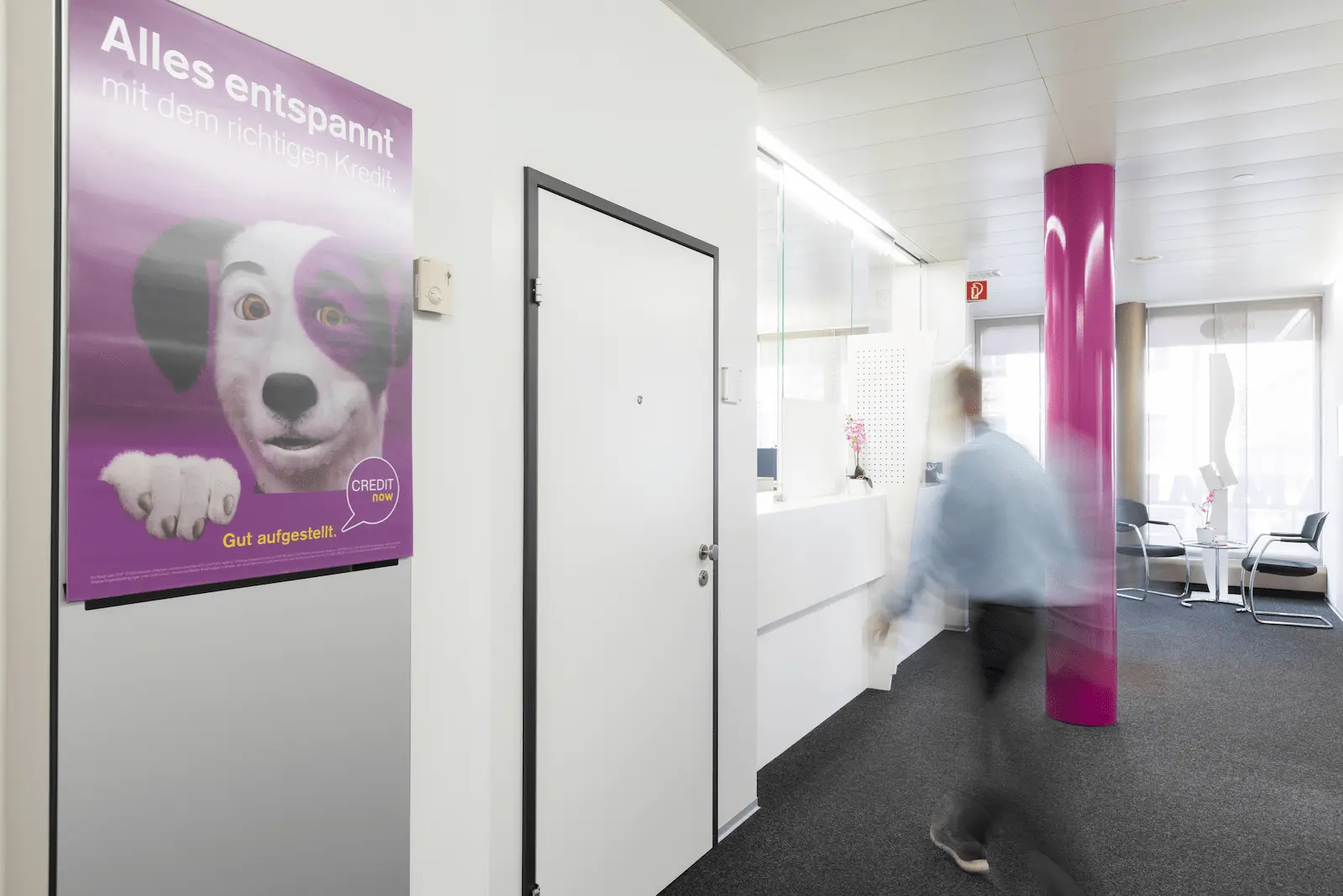 Schalterbereich der BANK-now Filiale Zürich mit Plakat und hellem Innenraum.