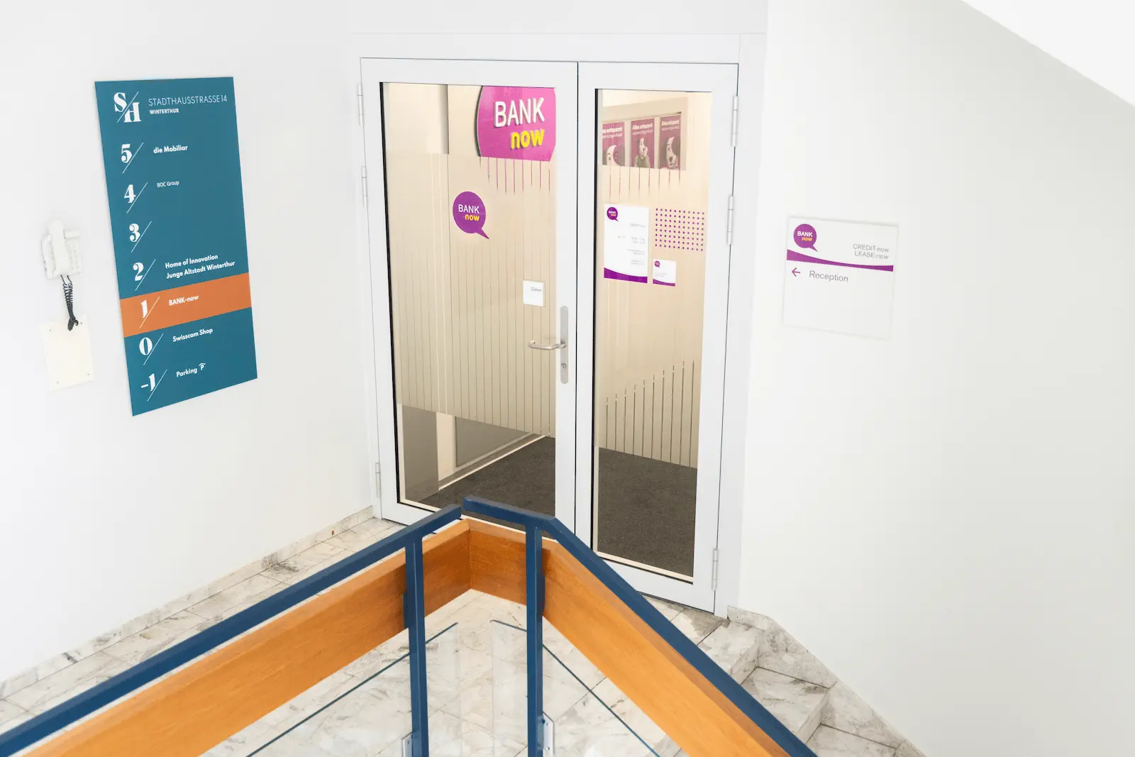 Innerer Eingangsbereich der BANK-now Filiale Winterthur mit Beschilderung und Glastüre.