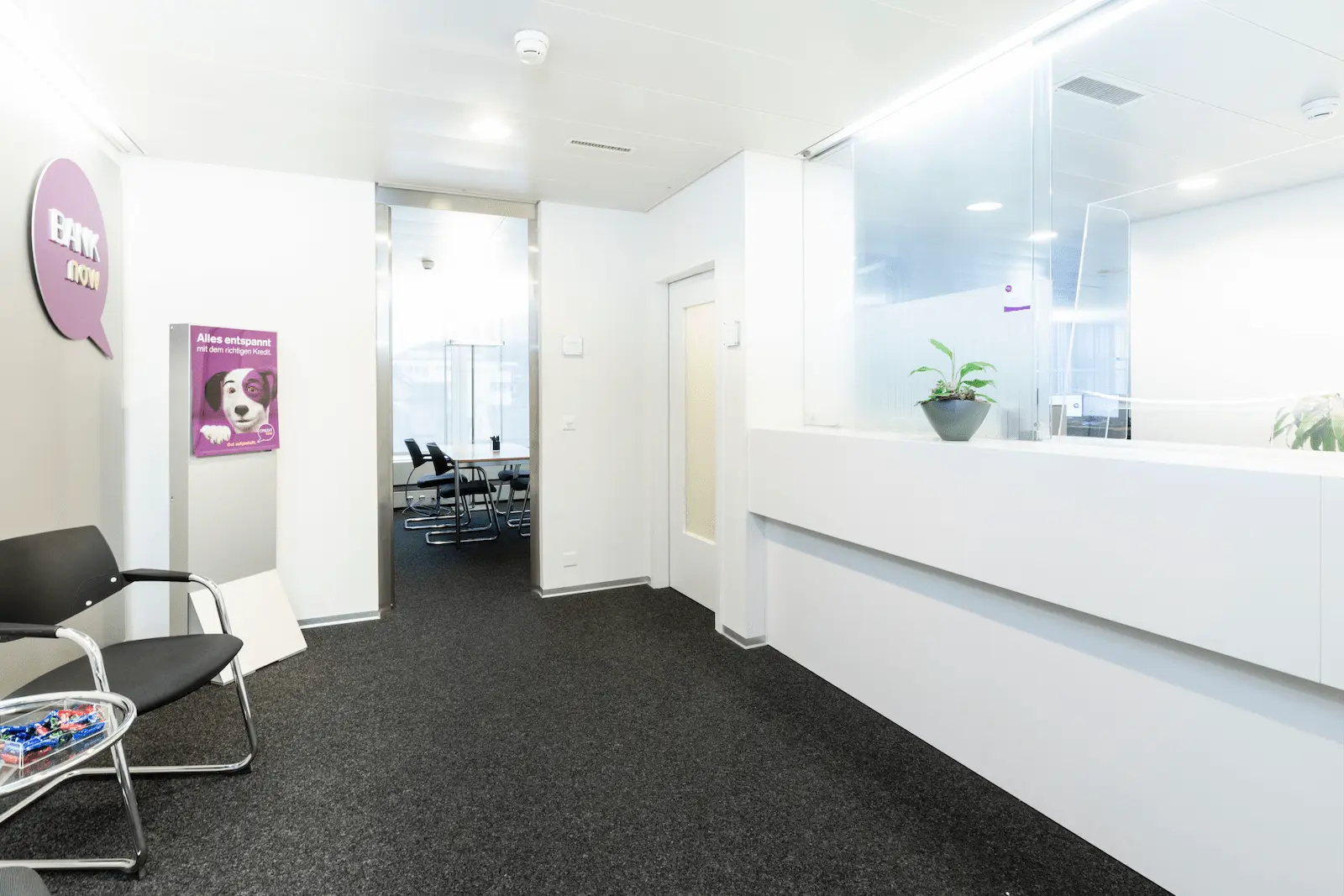 Wartebereich der BANK-now Filiale Baden mit Stühlen und Blick Richtung Empfang.