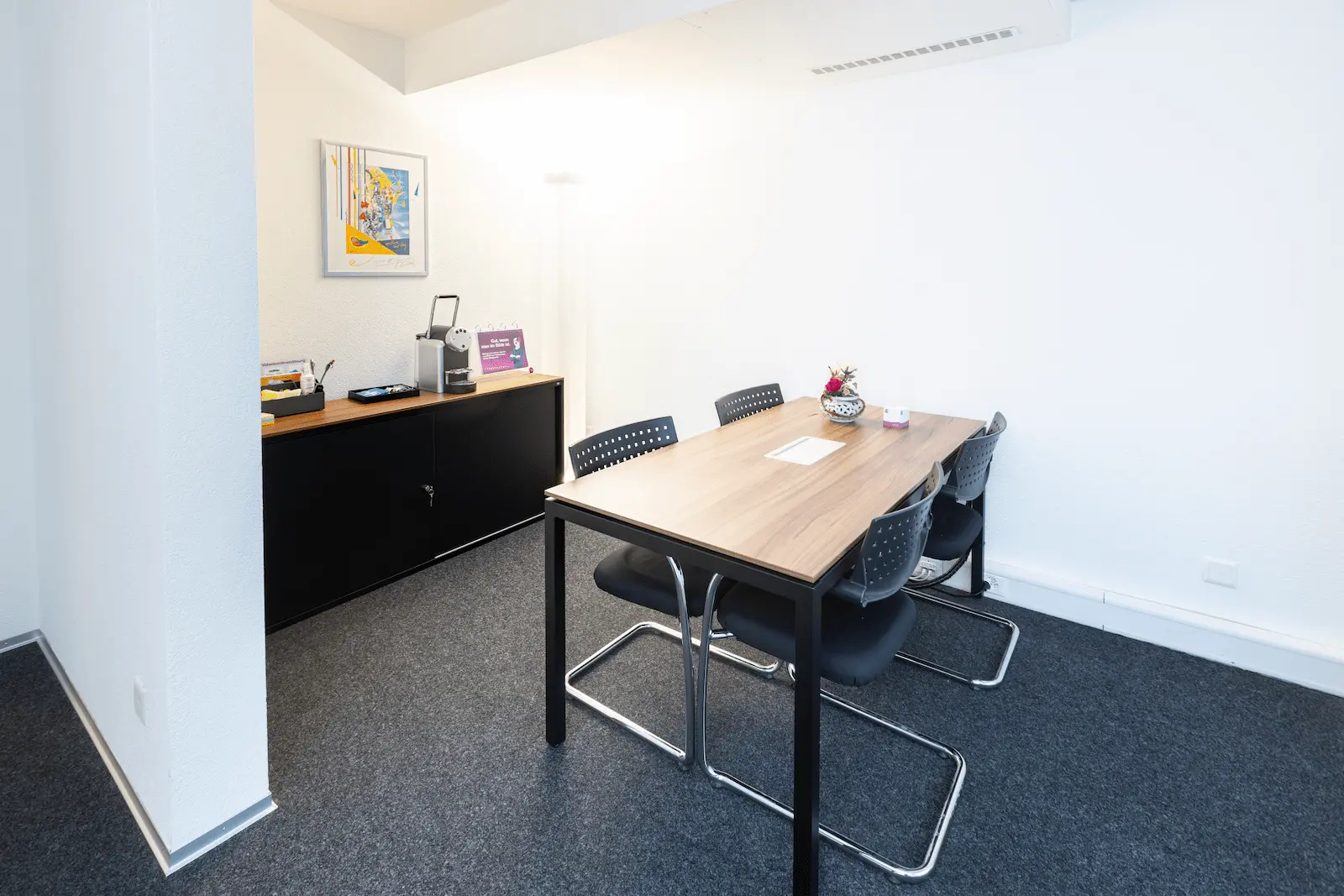 Besprechungsraum der BANK-now Filiale Bern mit Tisch, Stühlen und Sideboard im Hintergrund.